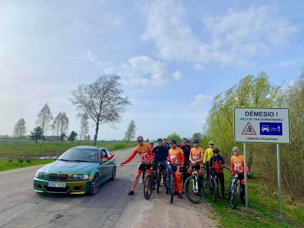 BMW car beside a group of cyclists holding a 1.5 meter measuring tape