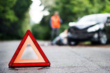 Car broken down in background and triangle hazard site out on road to warn other users.